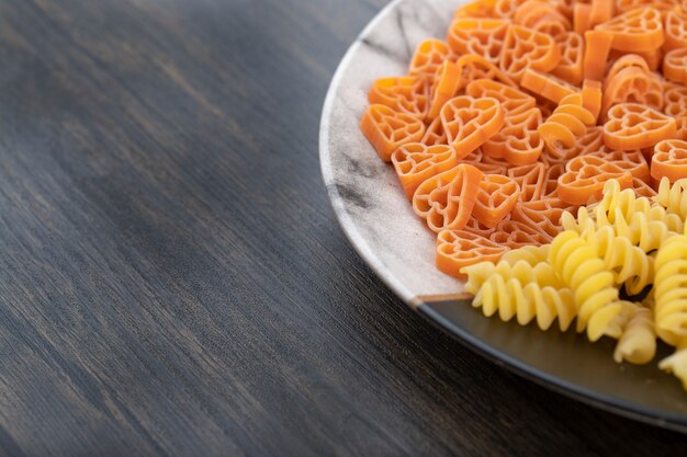 Placa de mármol de dos diferentes pastas crudas sobre mesa de madera.