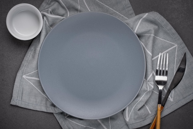 Placa mate gris vacía y servilleta gris sobre una mesa de piedra gris Copiar espacio para diseño de recetas o texto