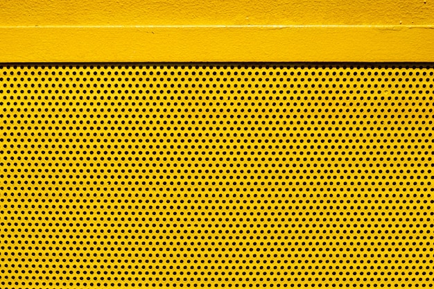 Foto placa de metal de color amarillo con muchos pequeños agujeros circulares puntos textura para el fondo