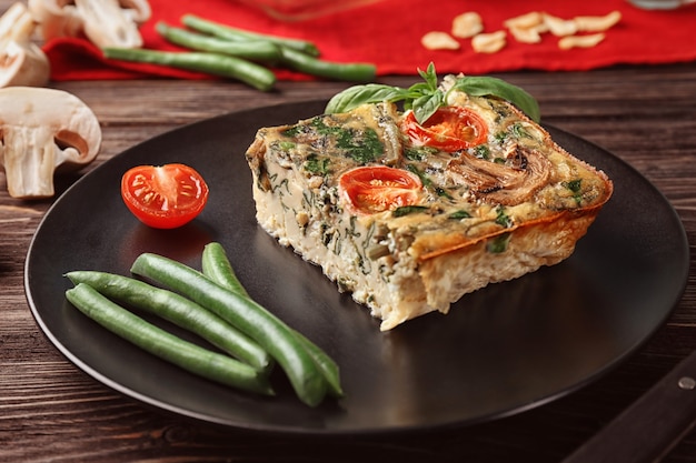 Placa negra con deliciosa frittata de espinacas en mesa