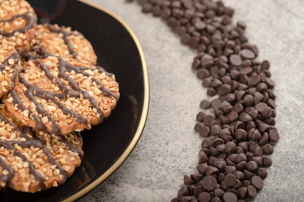 Placa negra de galletas de avena y caída de chocolate sobre la mesa de piedra.