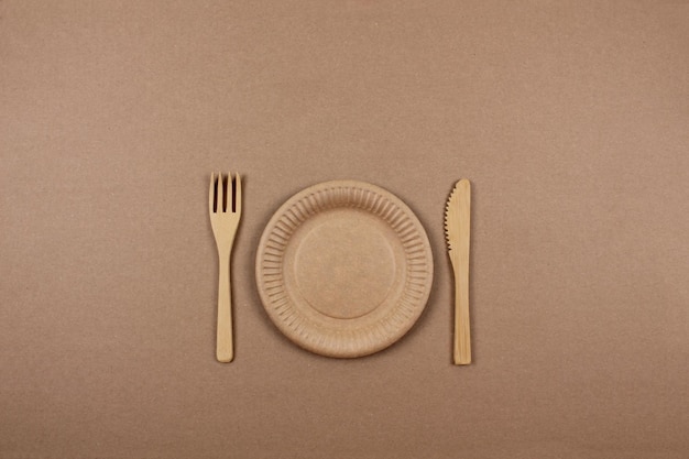Placa de papel tenedor de madera y cuchillo en el fondo de papel vajilla desechable hecha de materiales ambientales concepto de utensilios de cocina ecológicos vista superior espacio de copia