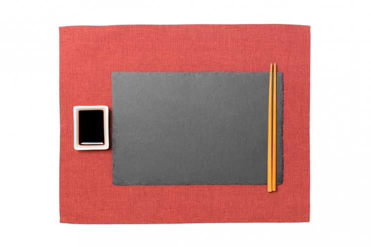 Foto placa de pizarra negra rectangular vacía con palillos para sushi y salsa de soja sobre fondo rojo servilleta