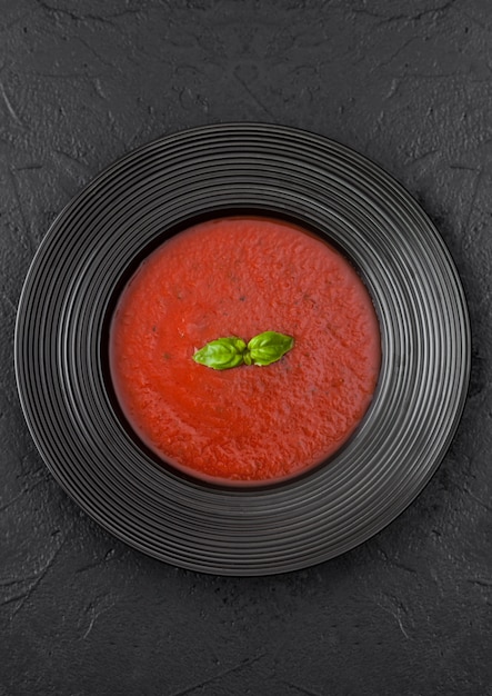 Placa preta do restaurante da sopa cremosa do tomate no preto. Vista do topo