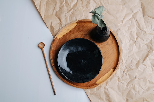 Placa preta e vaso em uma bandeja de madeira em uma composição de vista superior