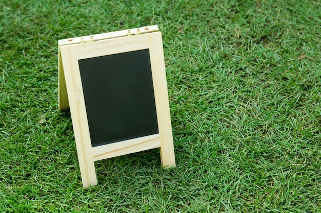 Foto placa preta em branco com cavalete no fundo da grama verde