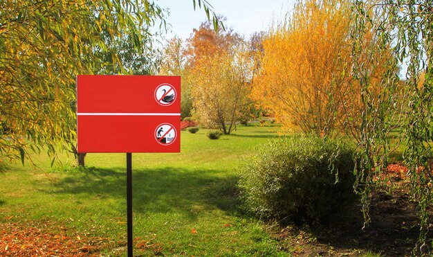 Placa que proíbe alimentar pássaros e jogar pedras no reservatório do parque. O mock up é gratuito.