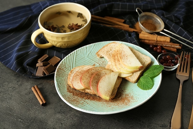 Placa con sabrosas tostadas de canela y rodajas de manzana en la mesa