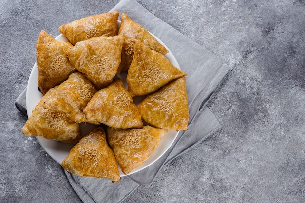 Placa con samsa delicioso de los samosas con la carne en el fondo gris, visión superior. Comida uzbeka