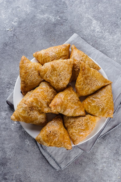 Placa con samsa samosas deliciosos con la carne en el fondo gris, visión superior. Comida uzbeka