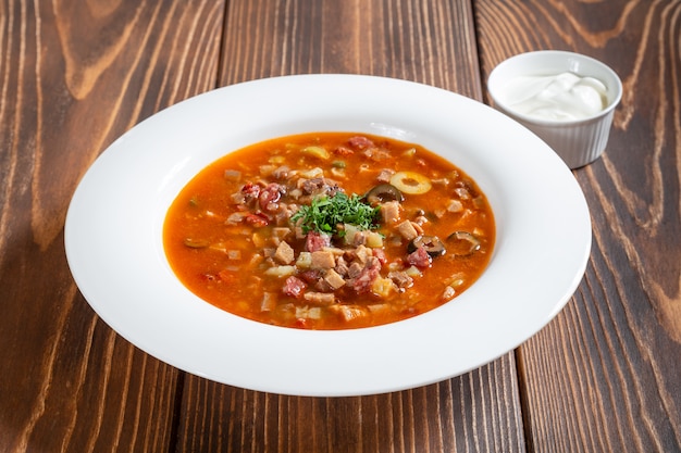 Placa tradicional sopa de carne rusa Solyanka en mesa de madera