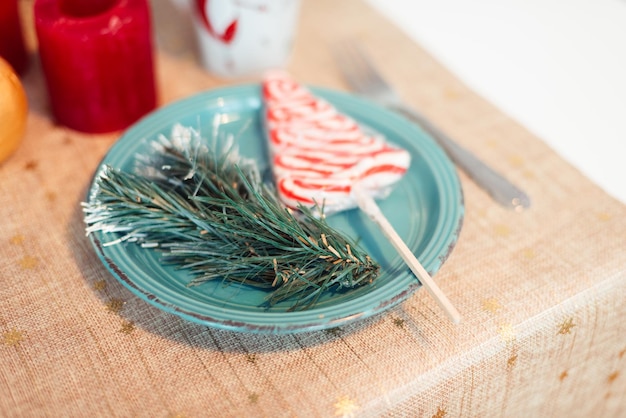 Placa turquesa na mesa com galho de árvore de natal e conceito de natal pirulito