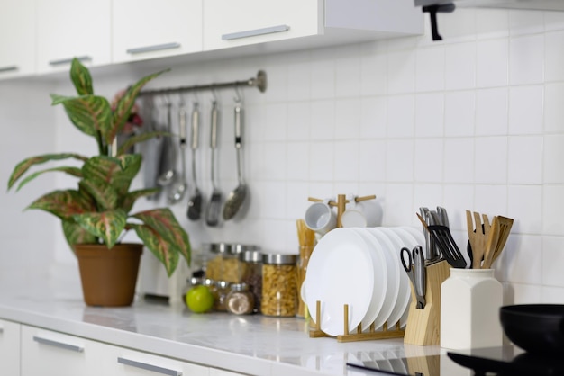 Placa y utensilios con herramientas decorativas en cocina blanca moderna.