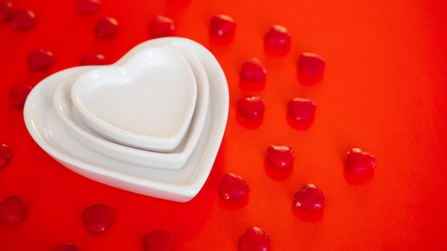 Placas blancas en forma de corazón sobre rojo con caramelo pequeño