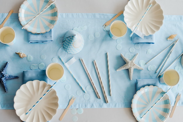 Placas de papel na mesa de aniversário preparada com para festa de crianças ou meninas nas cores azul e branco do céu. estilo do mar. chá de bebê menino. vista superior, plana