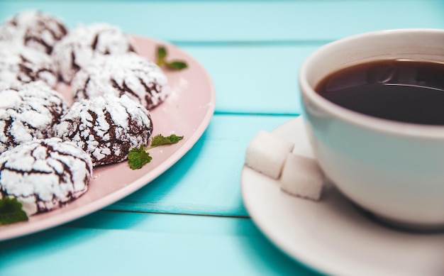 Plätzchen auf blauem Holztisch in einem Teller mit einer Tasse Kaffee