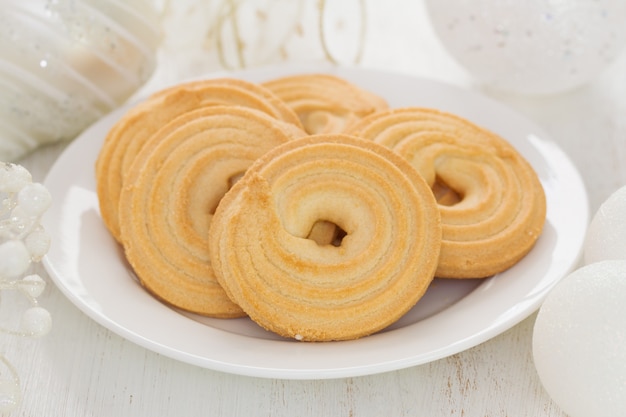 Plätzchen auf weißem Teller auf weißem Holz