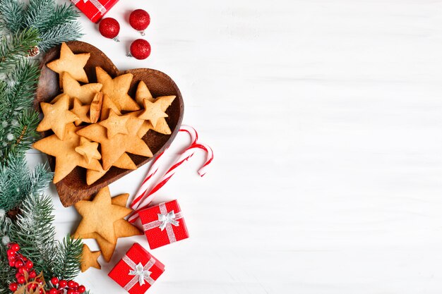 Plätzchen, Geschenke und Tannenbaumniederlassungen auf einem weißen Holztisch