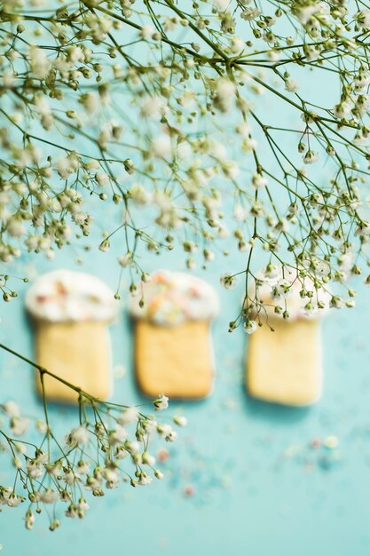 Plätzchen in Form von Ostern backt auf einem blauen Hintergrund unter den Blumen von Gypsophila zusammen