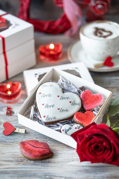 Plätzchen oder Lebkuchenplätzchen in einer Geschenkbox mit einem roten Band auf einem Holztisch. Valentinstag.