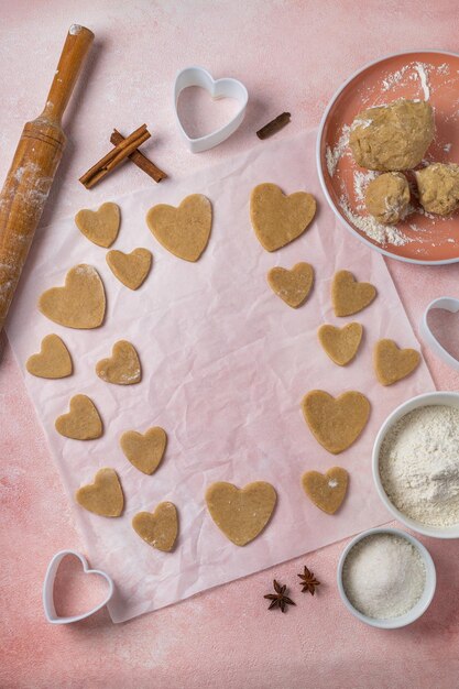 Plätzchen zum Valentinstag mit Zutaten auf rosafarbenem Hintergrund kochen