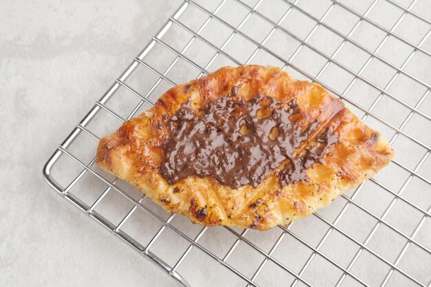 Plain Croissant Waffle ou Croffle com molho de chocolate servido em chapa branca sobre fundo cinza