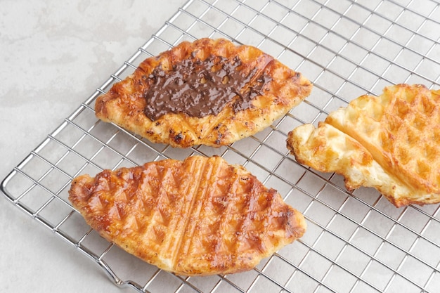 Plain Croissant Waffle ou Croffle com molho de chocolate servido em chapa branca sobre fundo cinza