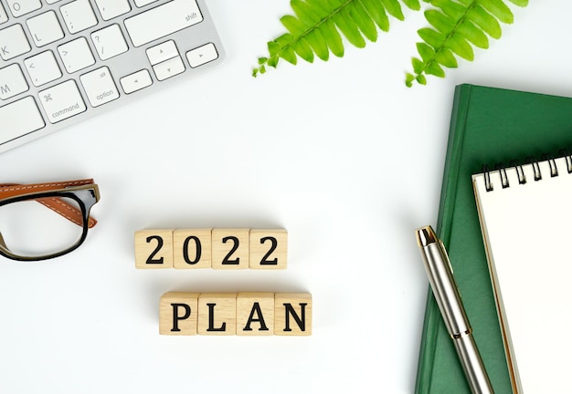 plan de año nuevo 2022 Planes teclado cuaderno y pluma PLAN 2022 la palabra está escrita en un bloque de madera