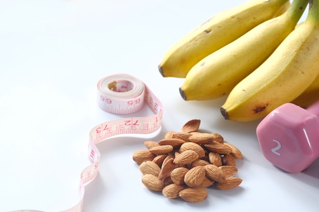 Plan de dieta con nuez de almendra, mancuernas, plátano en la mesa.