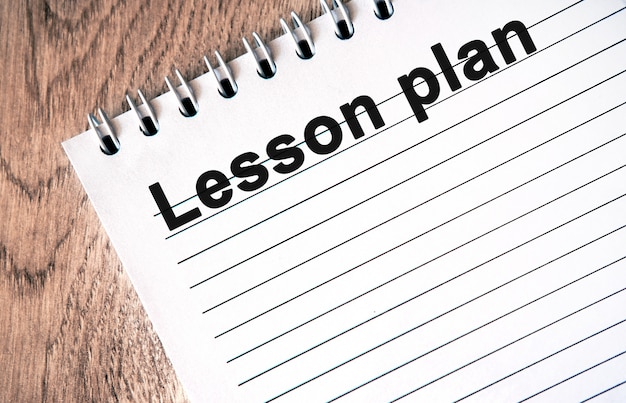 Plan de lección: texto negro en un cuaderno blanco con líneas en una mesa de madera