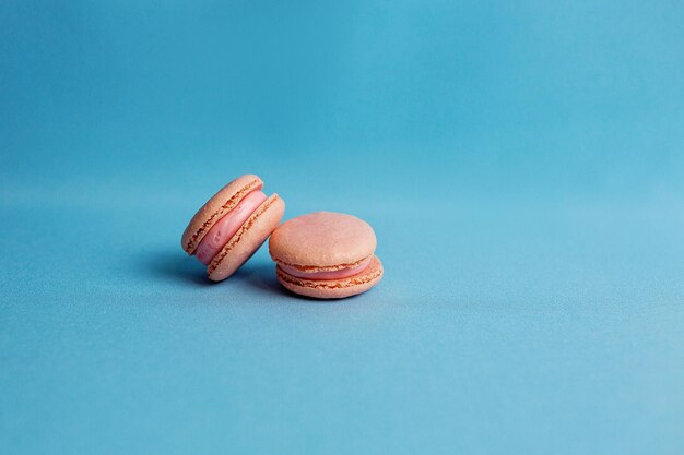 El plan medio de un pastel colorido con galletas de almendras en colores pastel sobre un fondo azul.