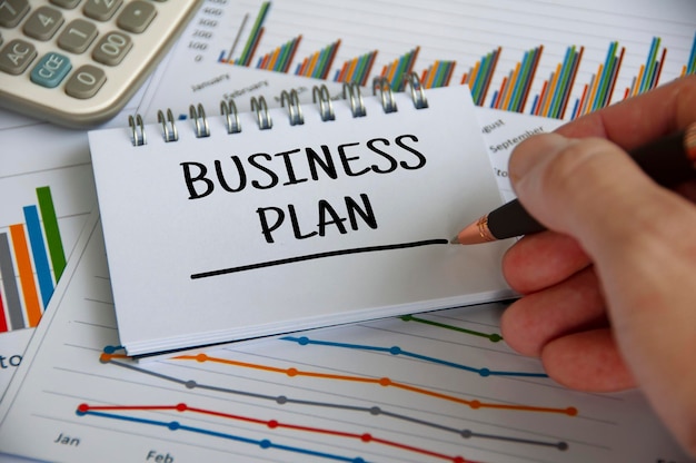 Foto plan de negocios escrito en el bloc de notas con fondo de análisis gráfico concepto de plan de negocios
