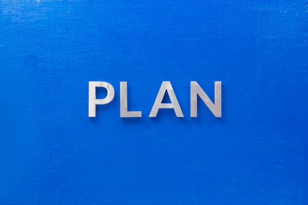 El plan de palabras colocado con letras de metal plateado en tablero azul en plano con composición central