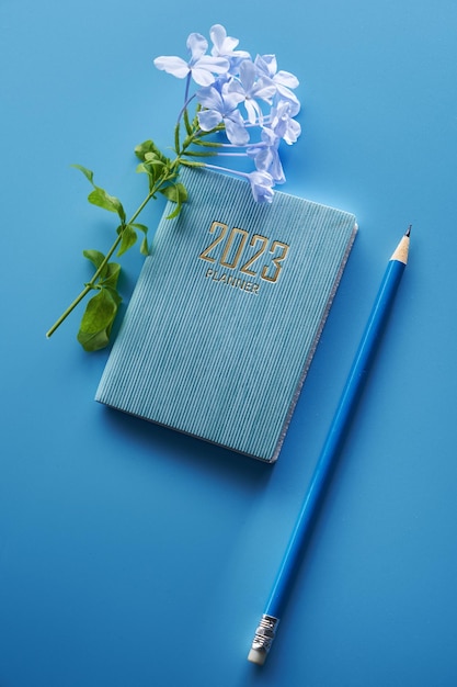 planejador de 2023 e flor roxa contra fundo azul
