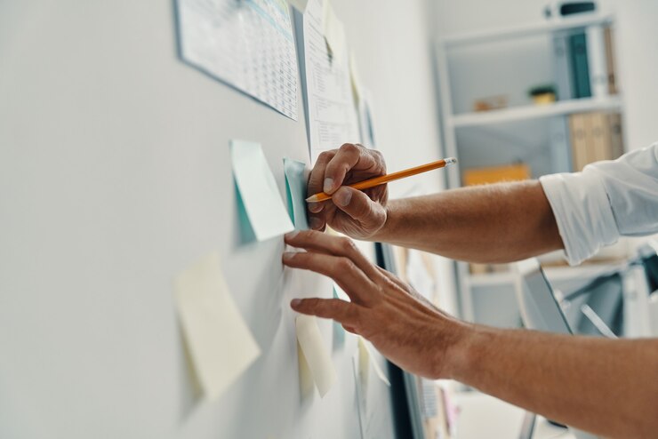 Foto planejamento de negócios. close de um homem escrevendo algo usando notas adesivas enquanto trabalha no escritório