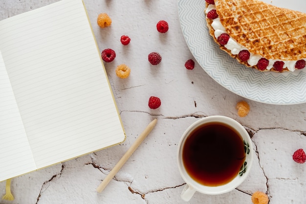 Planejamento de negócios matinal com caneta, xícara de chá e waffle ecológicos