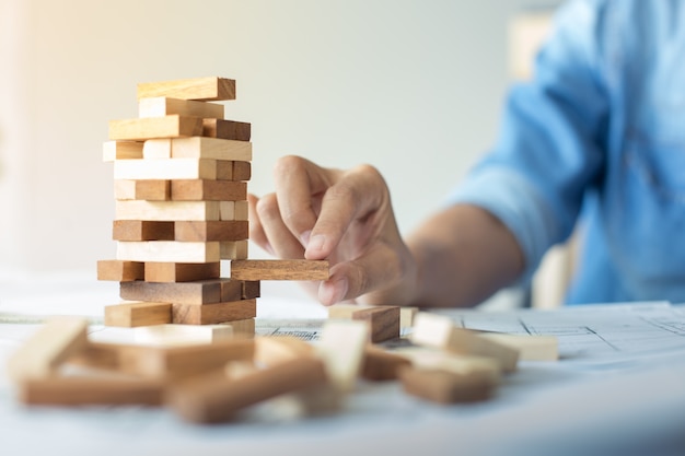 Planejamento, risco e estratégia em negócios, empresários e engenheiros apostando colocar bloco de madeira em uma torre.