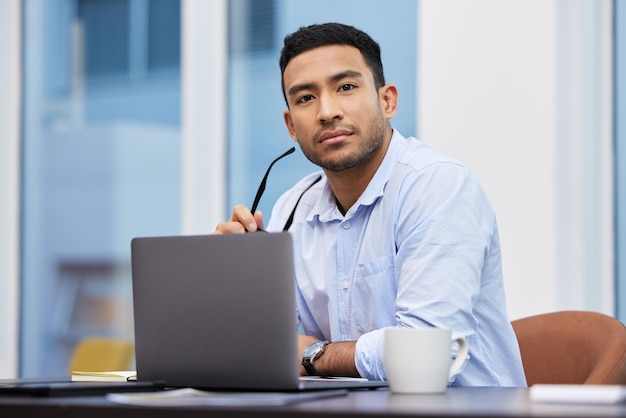 Planejando meu próximo passo Foto de um jovem empresário bonito sentado sozinho em seu escritório e usando seu laptop