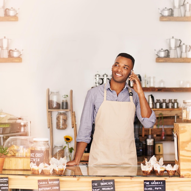 Foto planen sie ein lächeln und ein telefongespräch mit einem schwarzen mann in einem café für die kommunikation, das netzwerk oder den dienst im café-restaurant und denken sie mit einem glücklichen jungen kleinunternehmer oder verkäufer, der in einer bäckerei arbeitet