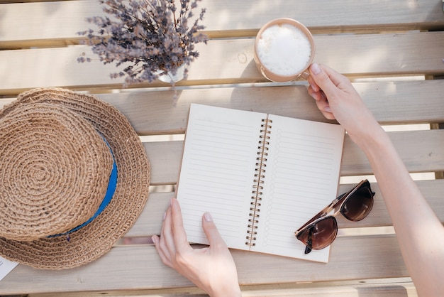 Planifica tu día. Chica joven con un cuaderno toma una taza de café. Vista superior