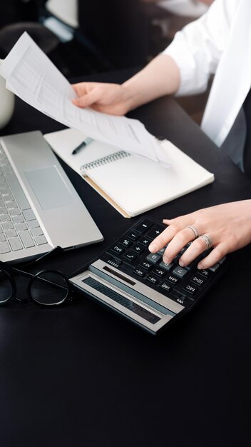 Planificación financiera exitosa Mujer de negocios en contabilidad Primer plano de la contadora en el trabajo Documento y calculadora en la mano Evaluación eficiente del presupuesto Mujer de negocio en finanzas