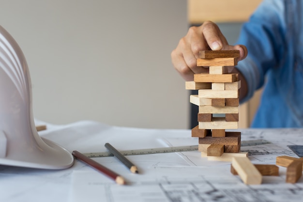 Planificación, riesgo y estrategia en los negocios, empresario y ingeniero de juegos de azar colocación de bloques de madera en una torre.