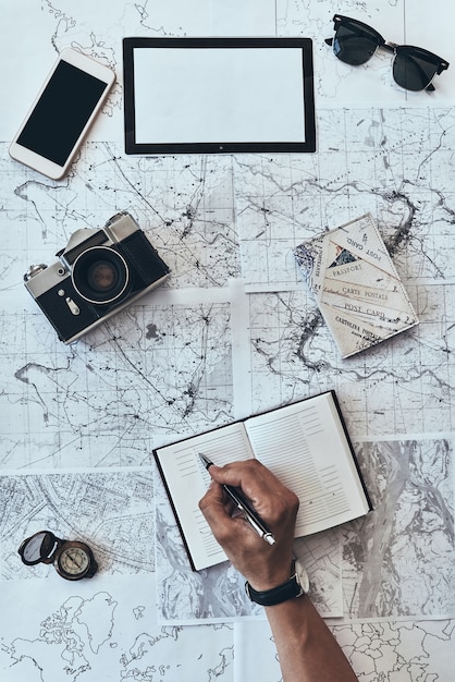 Foto planificación de viajes. cerrar vista superior del hombre escribiendo algo en el diario con gafas de sol