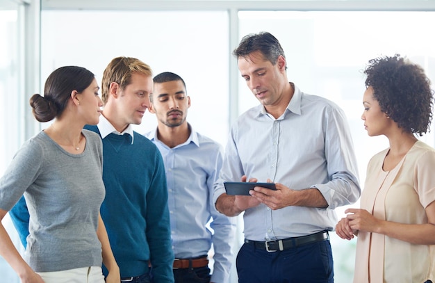 Planificando el camino en línea Foto de un grupo de colegas usando una tableta digital juntos