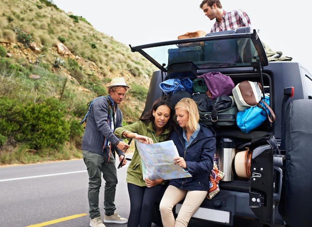 Planificando el viaje por carretera perfecto Un grupo de jóvenes amigos preparándose para su viaje de campamento