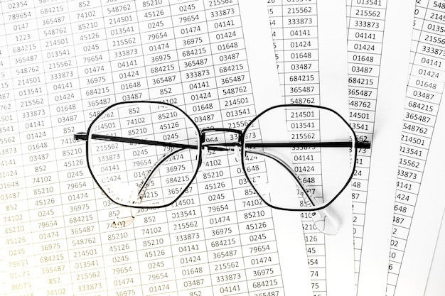 Planilhas ou relatórios mostrando figuras por meio de óculos. óculos do close up no relatório financeiro. Contabilidade. dados financeiros. Conceito de pesquisa de negócios e finanças.
