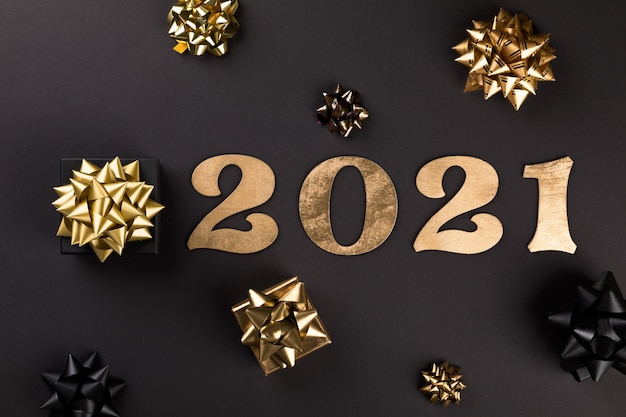 Foto plano de año nuevo con números de oro 2021, regalos y lazos dorados