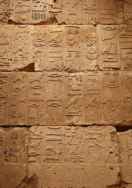 Plano aproximado de parede de pedra antiga com hieróglifos egípcios antigos esculpidos, vista frontal