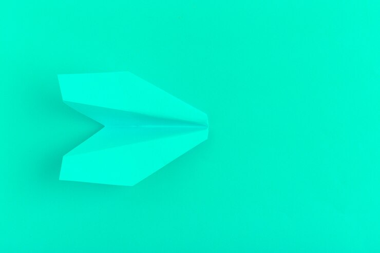 Foto plano de un avión de papel en verde pastel.