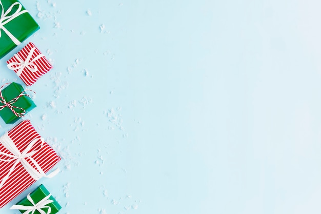 El plano azul de Navidad y año nuevo yacía con varias cajas de regalo presentes en rojo, blanco y verde vista superior. Cinta de regalo y papel de embalaje. Copos de nieve del destino. Copie el área de espacio para el texto. Foto de alta calidad
